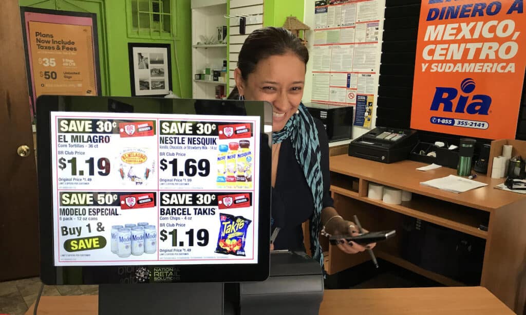 A cell phone store owner has one customer facing screen pos hardware at her business. The screen displays sales adds. Photo by NRS.