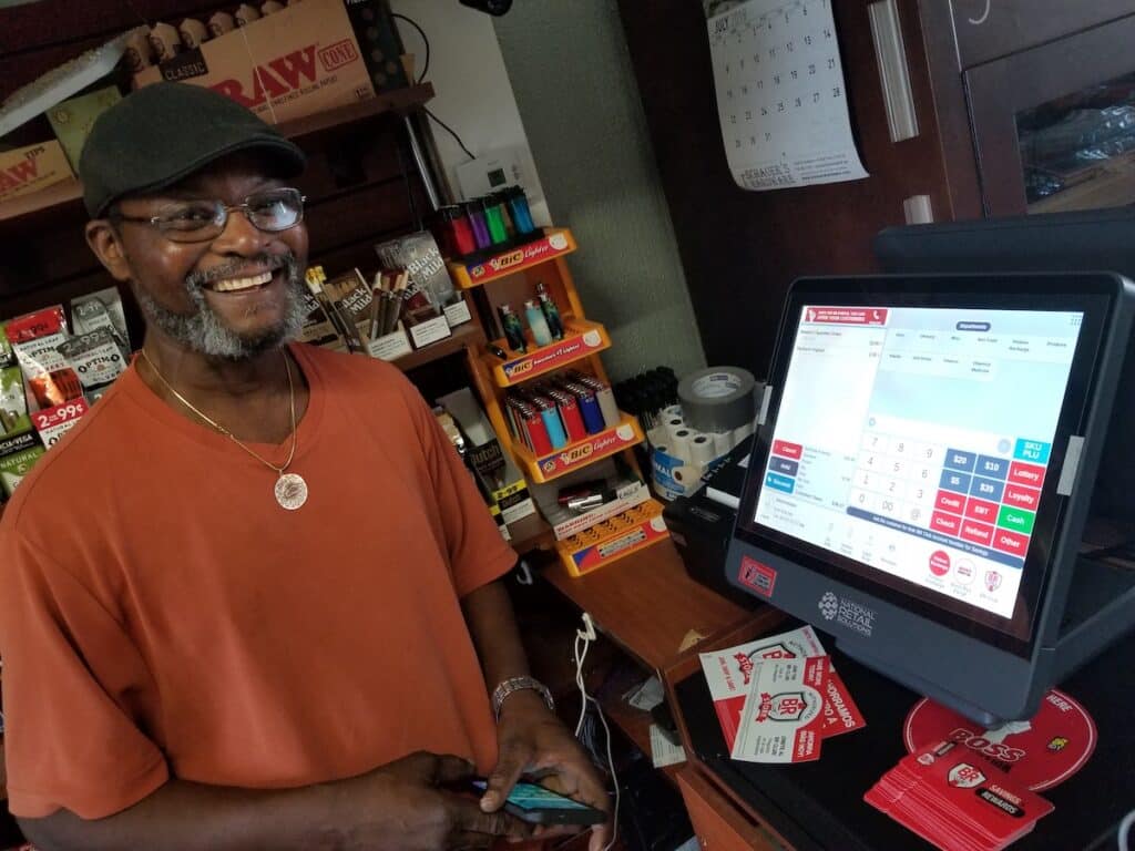 A bodega owner with his choice of POS hardware at his business.