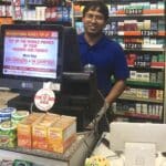 Convenience store owner behind the counter with two different point of sale systems