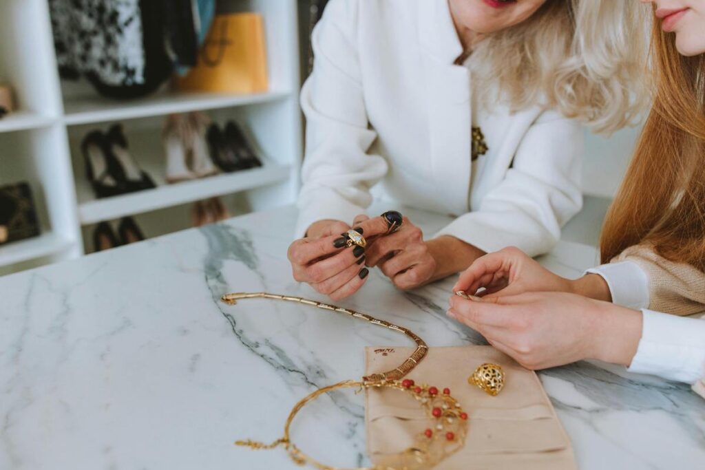 A store owner helps a client choose jewelry. Stock photo.