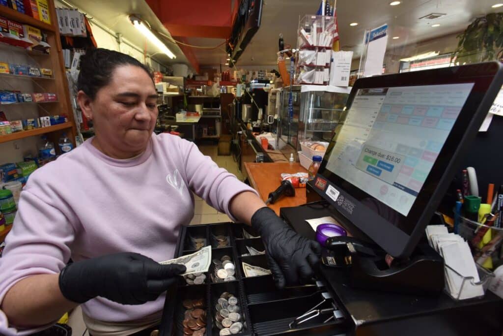 Cash Advance Funding: Retailer opens the cash drawer at a grocery store in Newark. Photo by NRS.