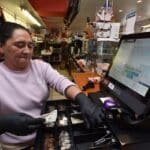 Cash Advance Funding: Retailer opens the cash drawer at a grocery store in Newark. Photo by NRS.