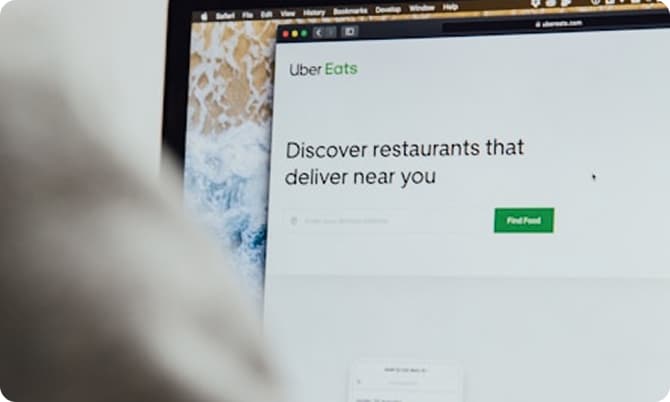 A laptop screen displaying the Uber Eats website with the text "Discover restaurants that deliver near you