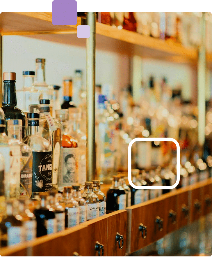 Bottles of liquor on a wooden shelf, with a bottle labeled "TANG" in the foreground